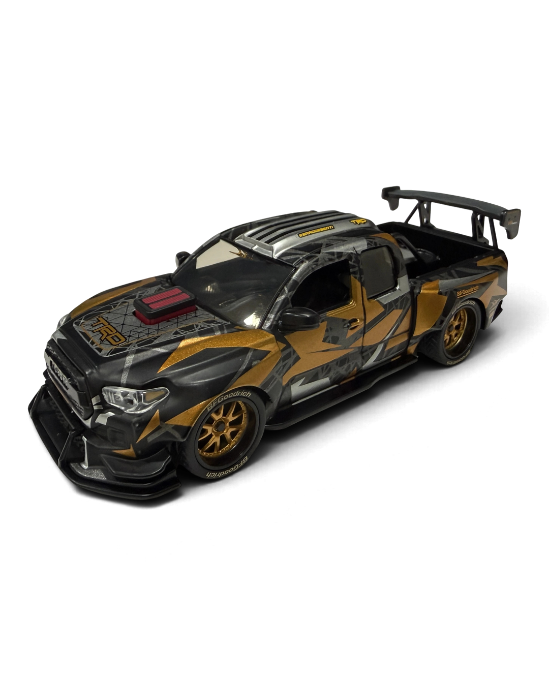 VaultifyUK Hot Wheels Premium 1:43 DeBerti Toyota Tacoma diecast truck in black, grey, and orange camo with bronze wheels
