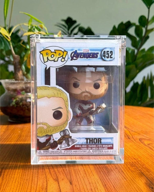 VaultifyUK premium acrylic display case protecting a boxed Thor Funko Pop figure on a wooden surface.