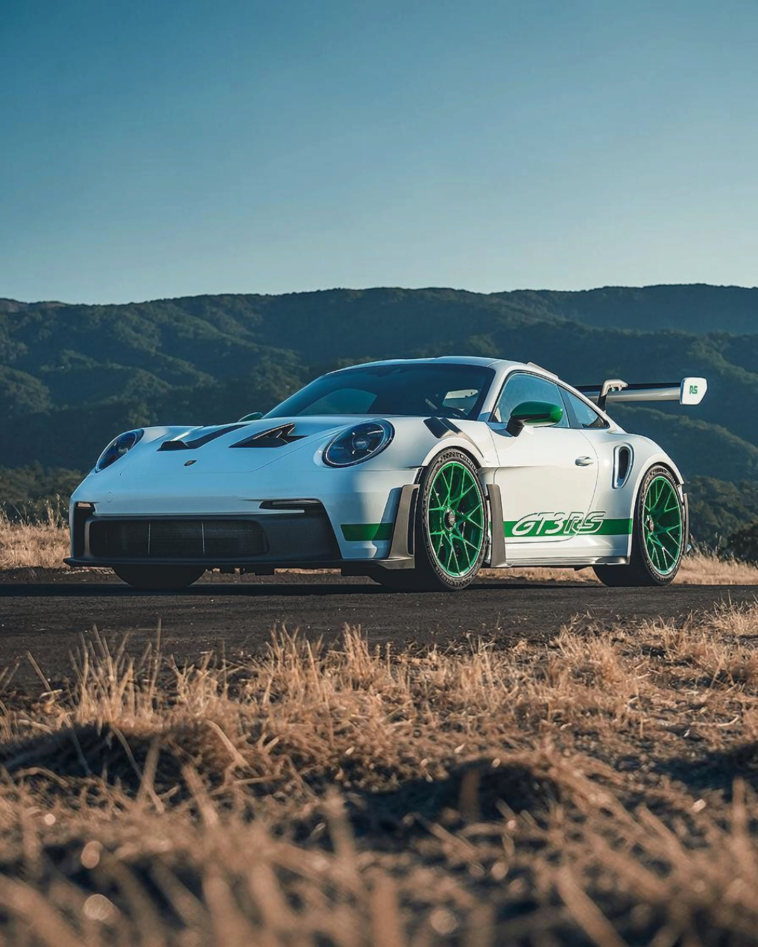 VaultifyUK Solido 1:18 scale white Porsche 911 GT3 RS model with Python Green wheels and accents on a scenic road