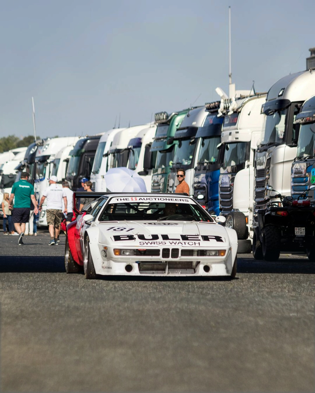 The real BMW M1 Procar: a white M1 Procar driving back to the paddock at a historic racing event