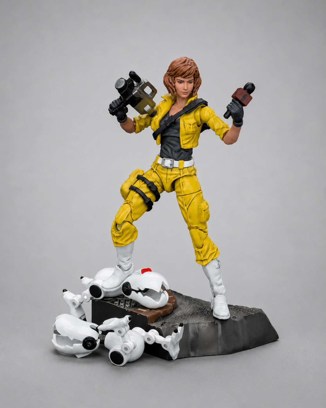 JoyToy TMNT April O’Neil figure posed with camera and microphone on a scenic base with damaged robot accessories