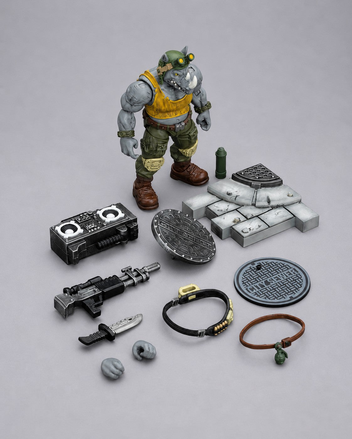 JoyToy TMNT Rocksteady action figure displayed with rifle, knife, boombox, sewer base, interchangeable hands and accessories