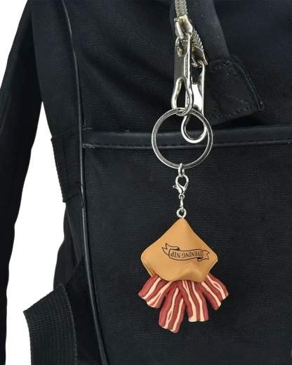 VaultifyUK Critical Role Taste of Exandria Pocket Bacon charm attached to a black backpack keyring