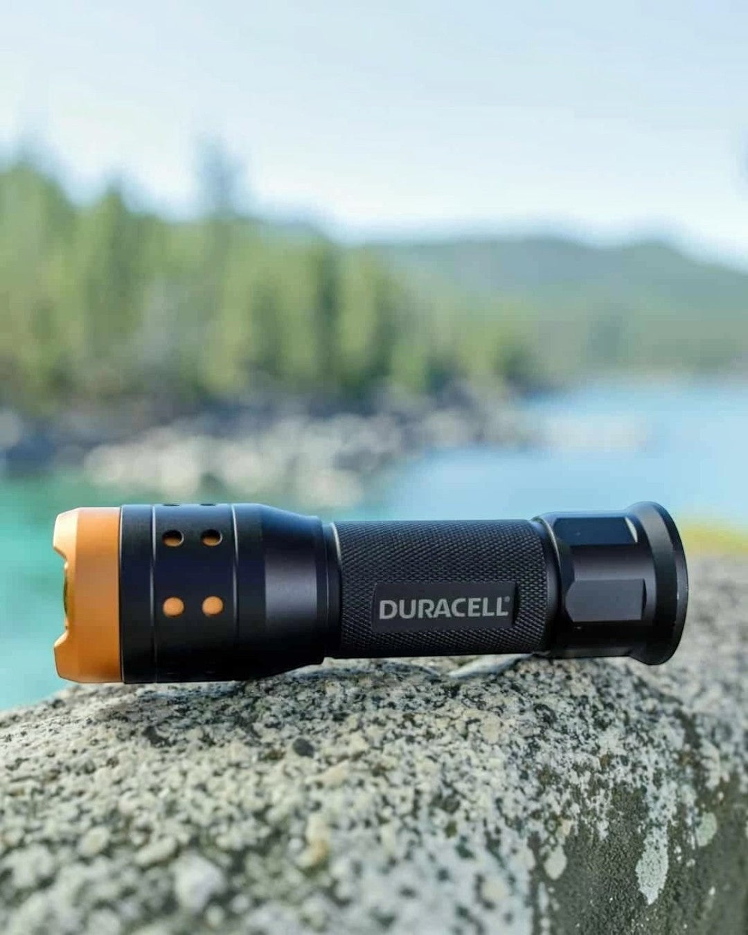 VaultifyUK Duracell 350 lumen LED flashlight with black aluminium body and orange bezel, resting on a stone ledge.