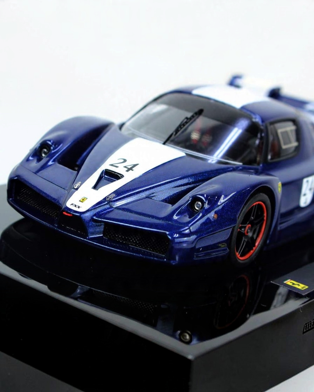 VaultifyUK Hot Wheels Elite 1:43 scale Ferrari FXX #24 diecast model car in blue and white livery on display base.