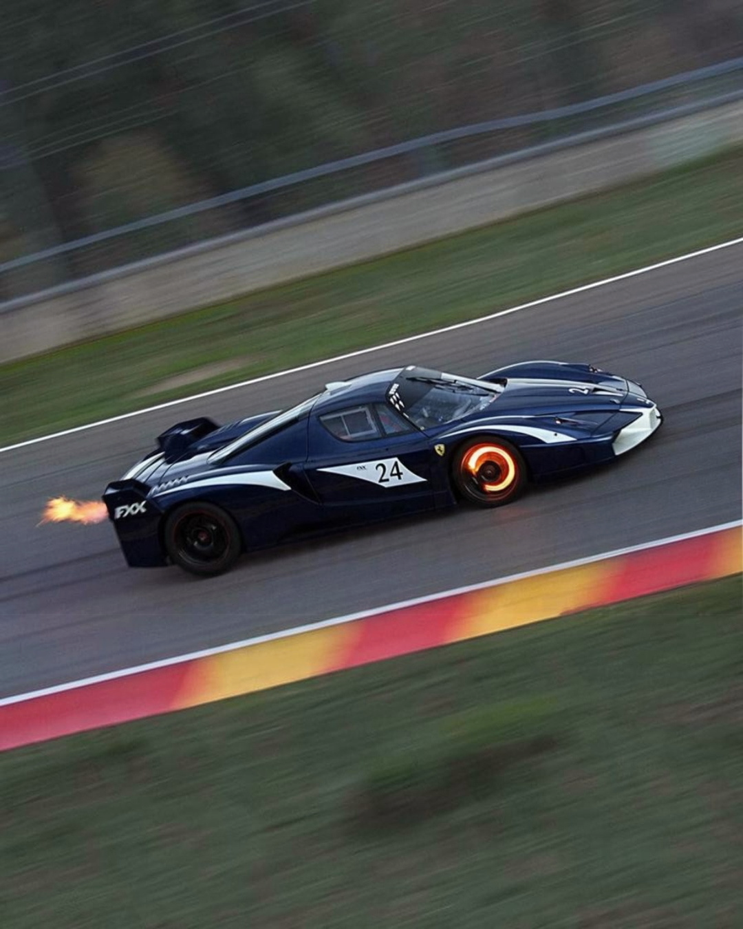 VaultifyUK Hot Wheels Elite 1:43 scale Ferrari FXX #24 diecast model car in blue and white livery on a race track.