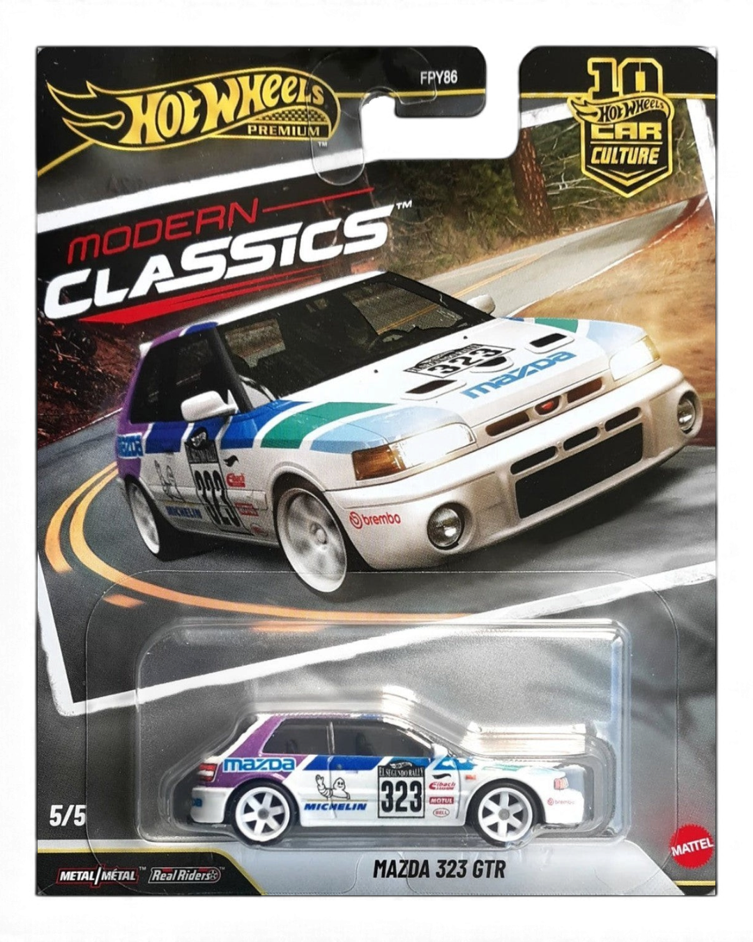 VaultifyUK Hot Wheels Premium Mazda 323 GTR rally car in white with purple and green livery on blister card packaging.