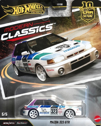 VaultifyUK Hot Wheels Premium Modern Classics Mazda 323 GTR die-cast car in blister packaging with rally livery.