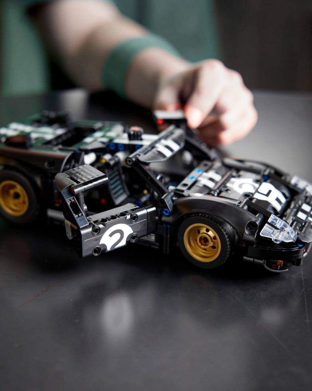VaultifyUK LEGO Technic 1966 Ford GT40 MKII race car model with open doors and metallic gold wheels on a dark surface