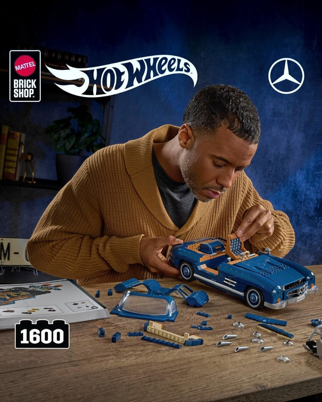 A man building a blue VaultifyUK Mattel Brick Shop Hot Wheels Mercedes-Benz 300 SL model car on a wooden desk.