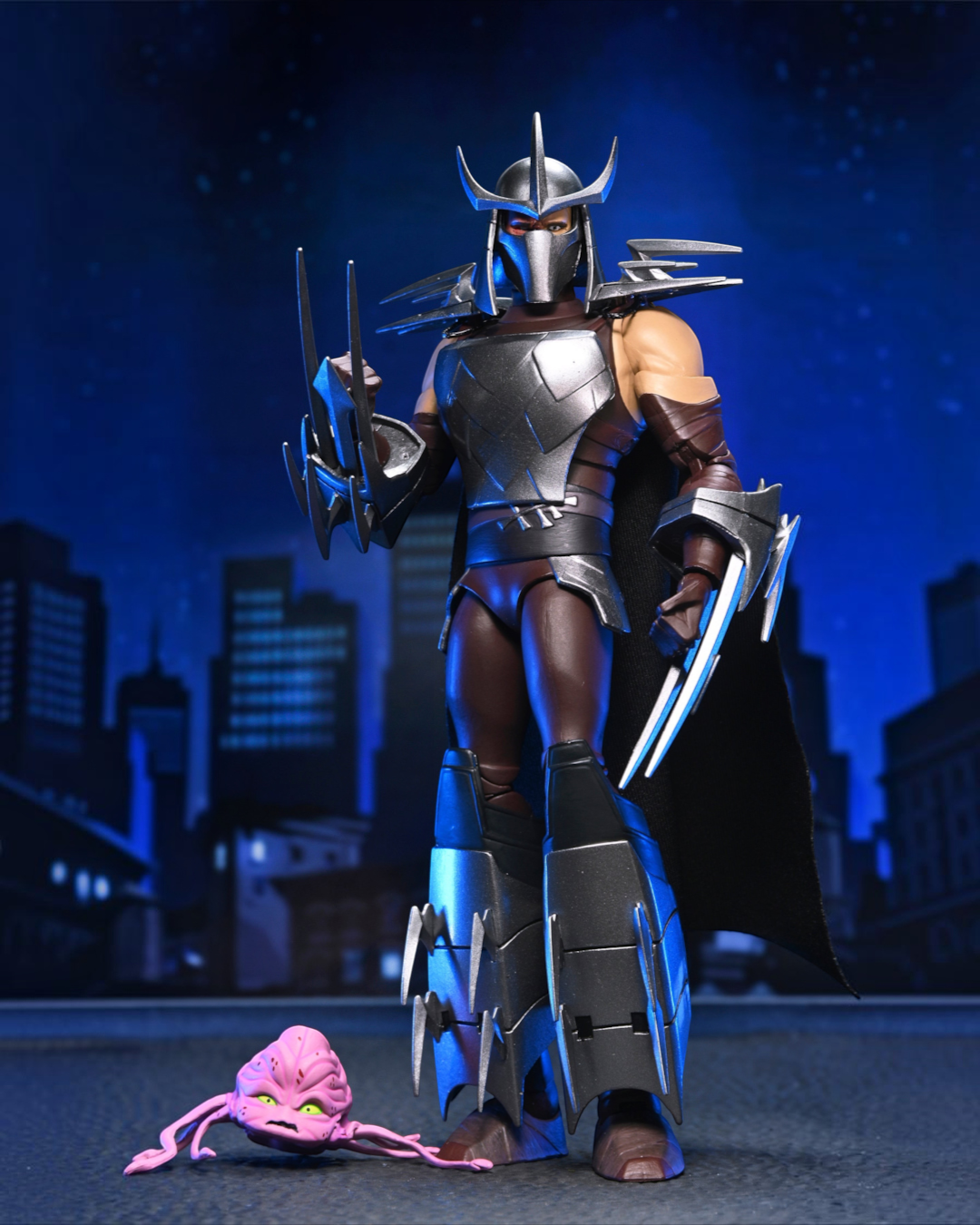 VaultifyUK NECA TMNT 2012 Shredder action figure with metallic armor, fabric cape, and a small pink Kraang figure.