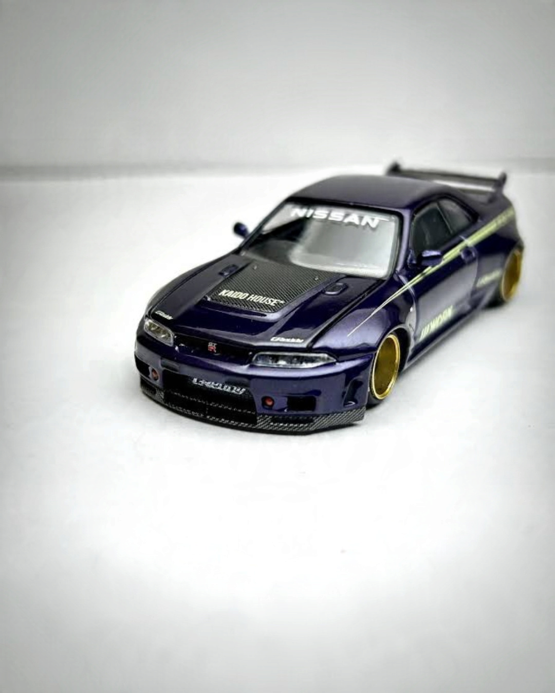 VaultifyUK Kaido House x MINI GT Nissan Skyline GT-R R33 in glossy purple with bronze wheels and carbon detailing.