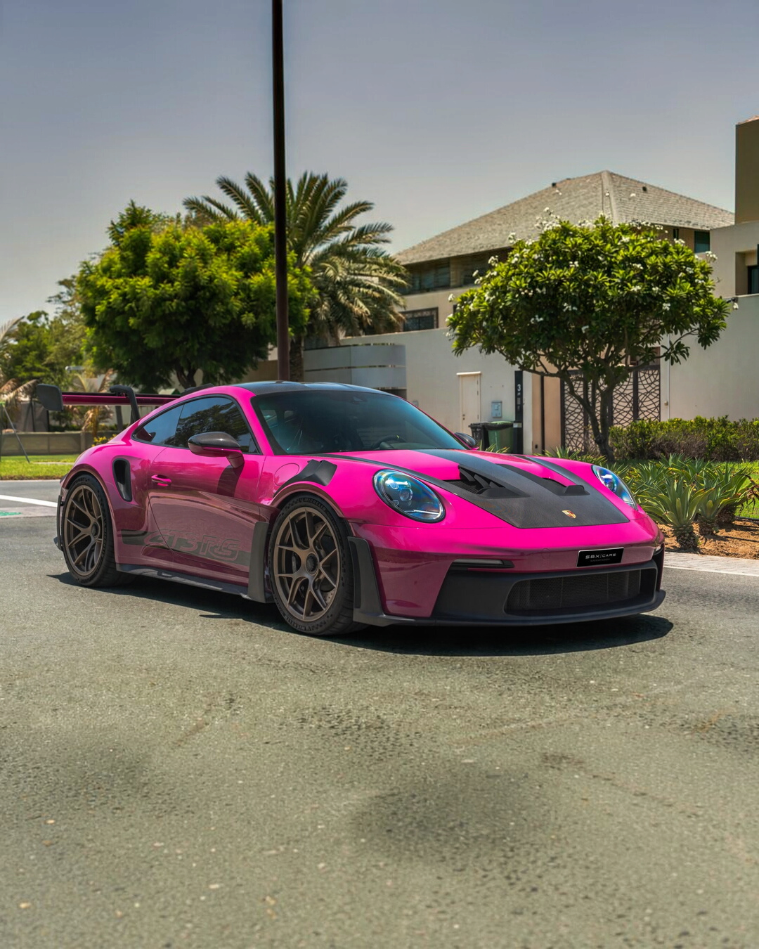 VaultifyUK Schuco 1:18 scale Porsche 911 992 GT3 RS model car in vibrant Rubystar magenta parked on a sunny street