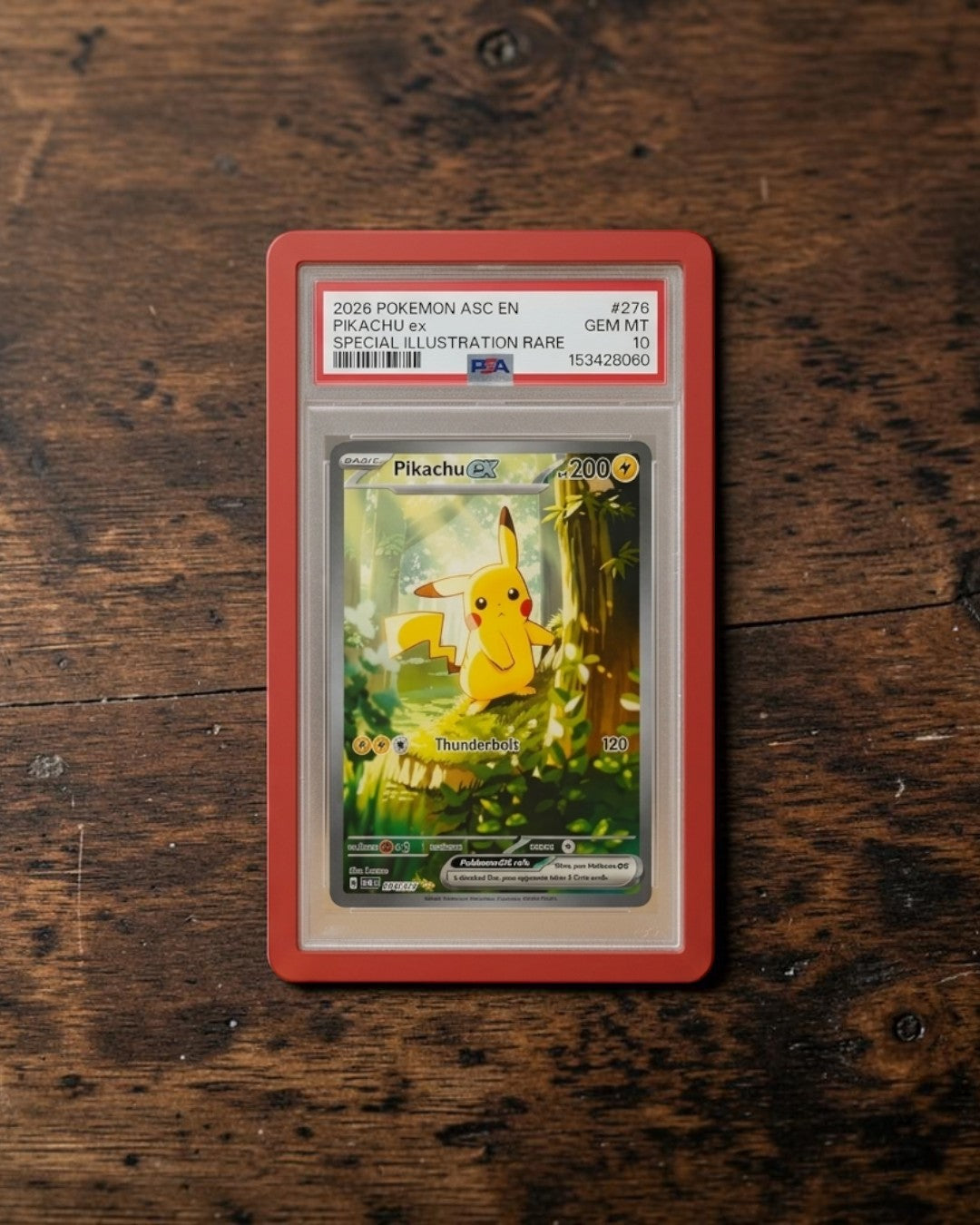 VaultifyUK Shield red TPU bumper protecting a PSA graded Pikachu Pokemon card slab on a wooden desk