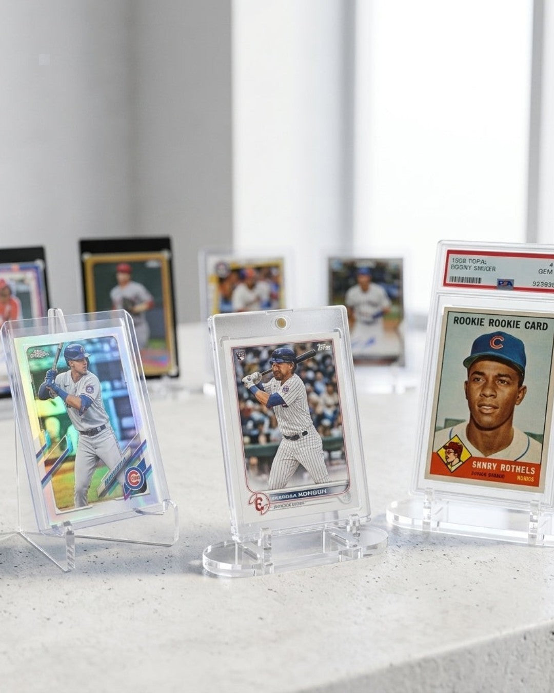 VaultifyUK Showcase clear acrylic stands displaying various trading cards and graded slabs on a white surface.